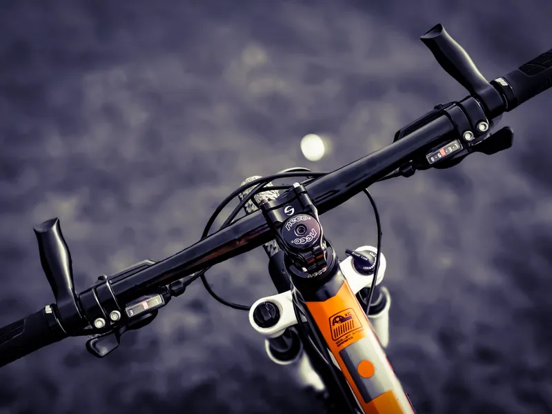 Manubrio de una bicicleta de montaña con el cuadro naranja, visto desde arriba